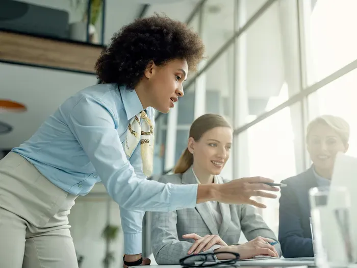 Diverse group of businesswomen in formal wear discussing work ideas during a meeting in a bright modern office, shown on towndirectorynetwork.com
